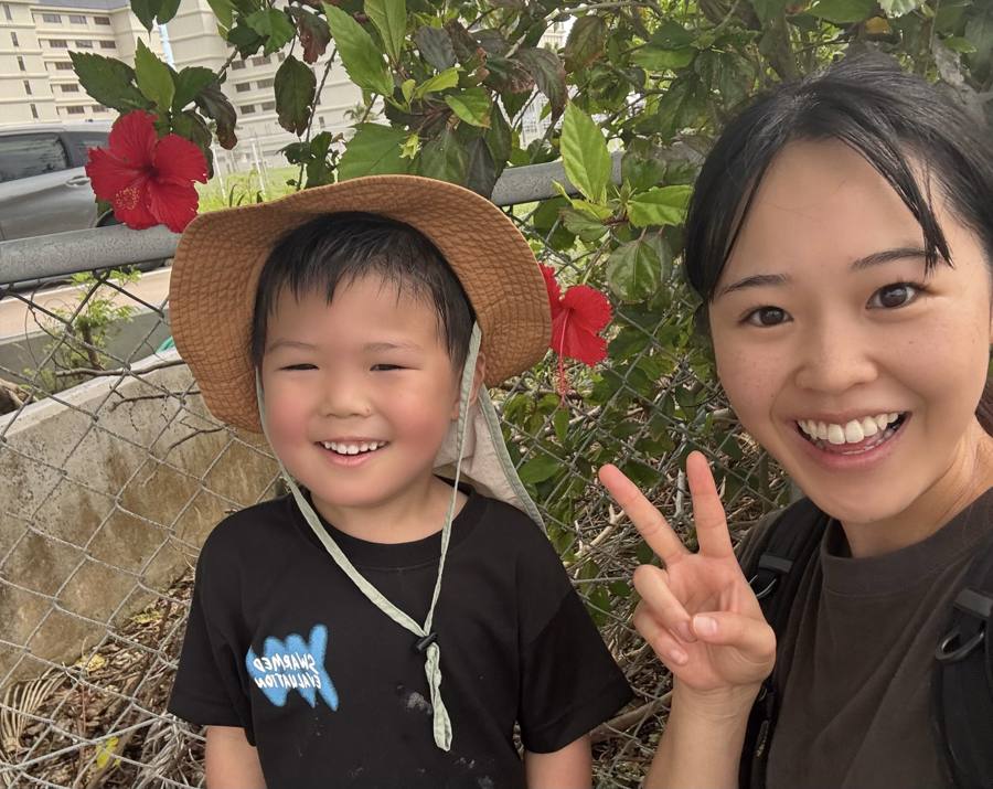 ハイビスカスの前で笑顔の男の子とシッター